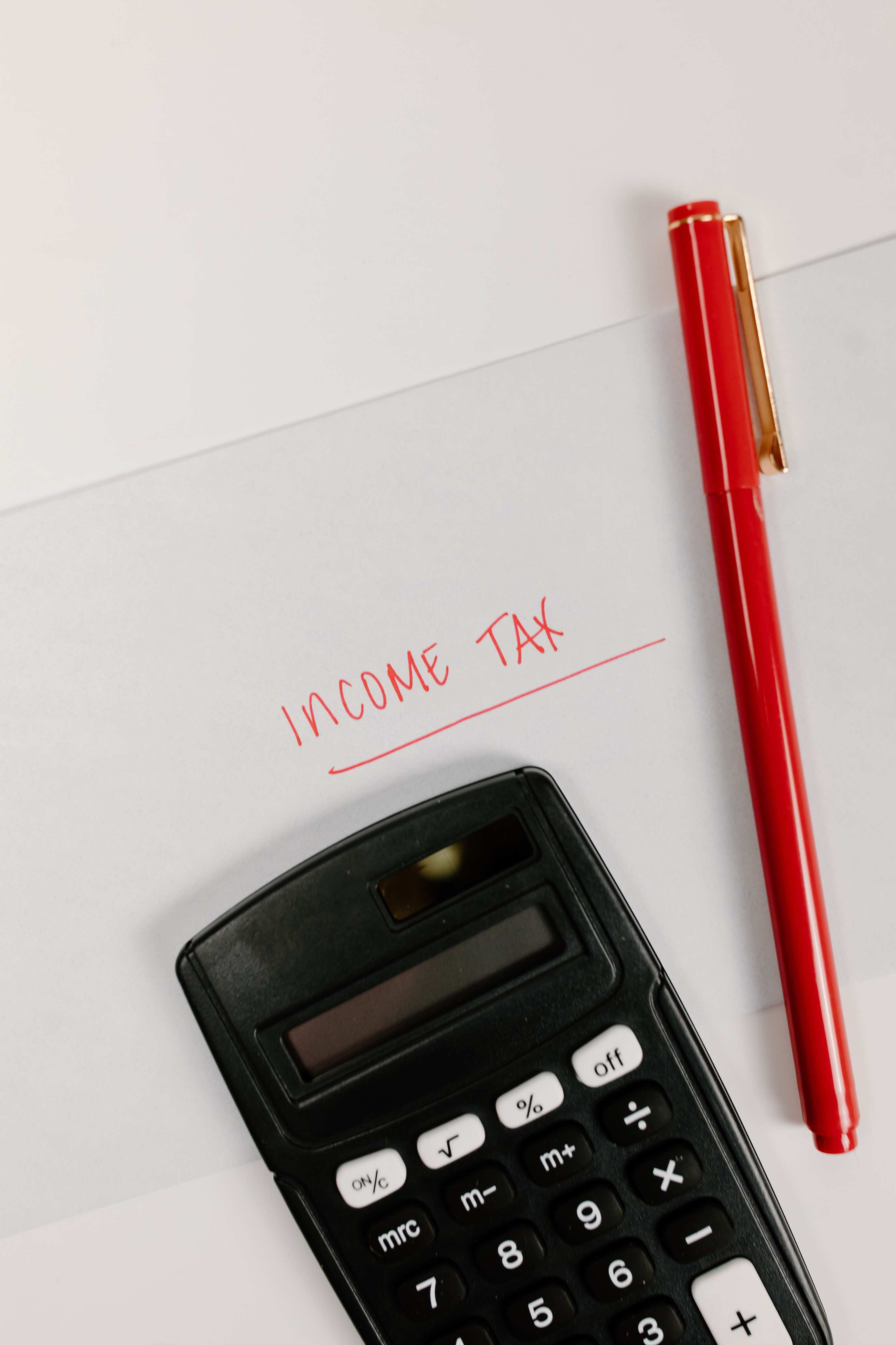 Taschenrechner, Stift und Unterlagen auf dem Tisch, Income Tax